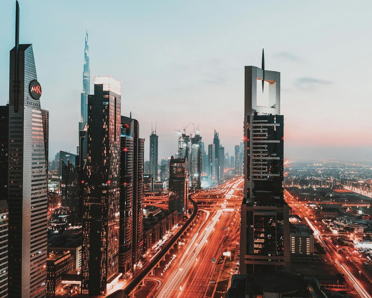 Dynamic view of Dubai's illuminated skyline featuring iconic skyscrapers at sunset.